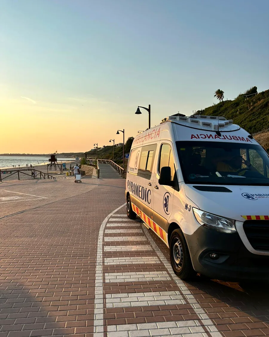 Ambulancia de Paramedic recorriendo el paseo marítimo de una playa gaditana al atardecer
